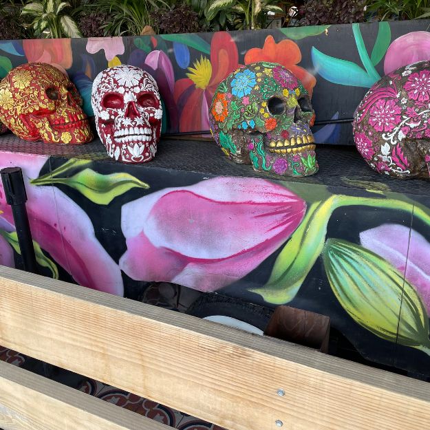 Decorative skulls with floral designs on a colorful bench in Mexico City.